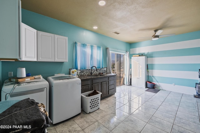 washroom featuring cabinets, sink, ceiling fan, separate washer and dryer, and a textured ceiling