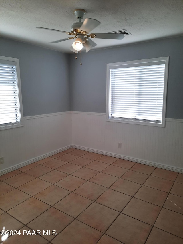 tiled spare room featuring a textured ceiling and ceiling fan