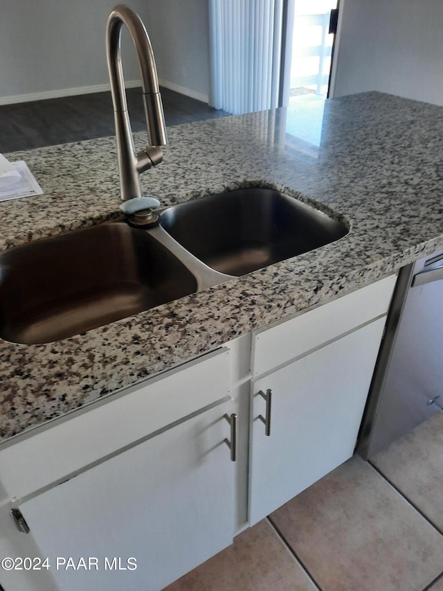 details with white cabinets, dishwasher, light stone counters, and sink