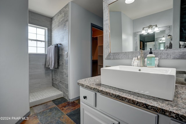 bathroom with a tile shower and vanity