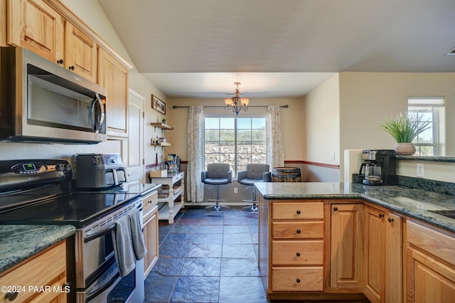 kitchen featuring appliances with stainless steel finishes, light brown cabinetry, an inviting chandelier, and dark stone counters