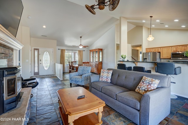 living room featuring ceiling fan, a wood stove, and high vaulted ceiling