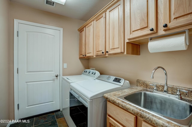 clothes washing area with washing machine and clothes dryer, sink, and cabinets