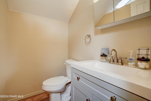 bathroom featuring vanity, toilet, wood-type flooring, and lofted ceiling