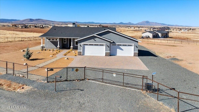 view of front of property featuring driveway, an attached garage, fence, and a mountain view