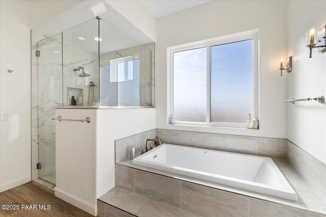bathroom featuring a marble finish shower, baseboards, a bath, and wood finished floors