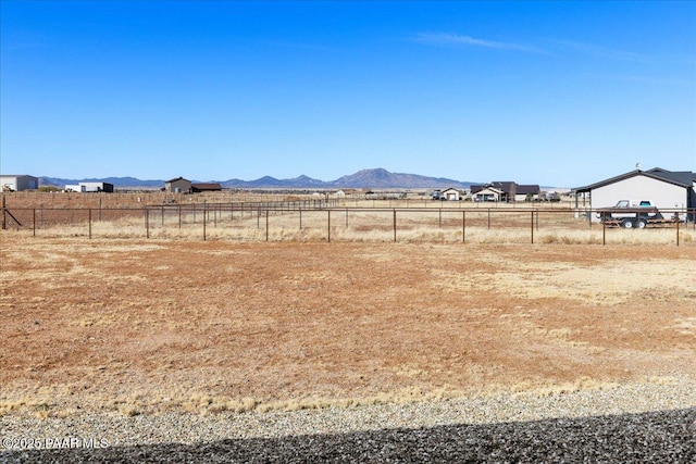 view of yard with a rural view, fence, and a mountain view