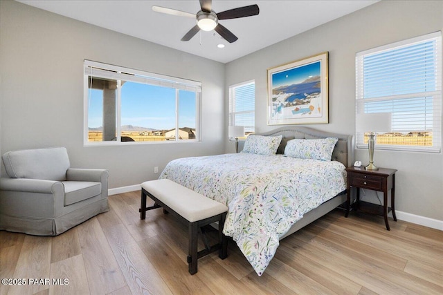 bedroom featuring light wood-type flooring, multiple windows, and baseboards