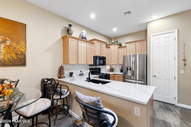 kitchen featuring black appliances, light brown cabinets, kitchen peninsula, and sink