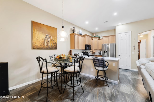 kitchen featuring hanging light fixtures, stainless steel refrigerator with ice dispenser, kitchen peninsula, decorative backsplash, and light brown cabinetry