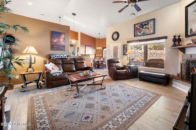 living room with light hardwood / wood-style floors and ceiling fan with notable chandelier