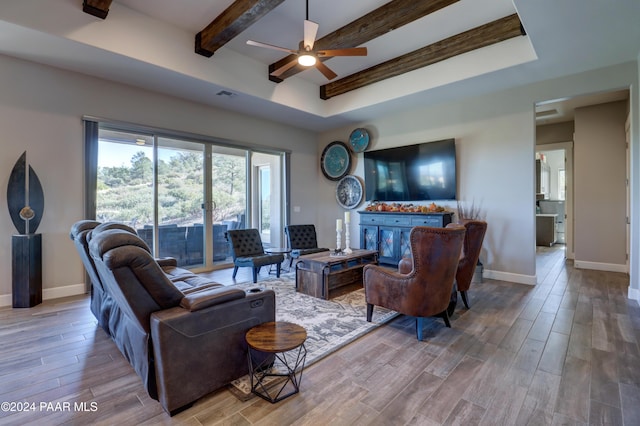 living room featuring beamed ceiling, light hardwood / wood-style floors, and ceiling fan