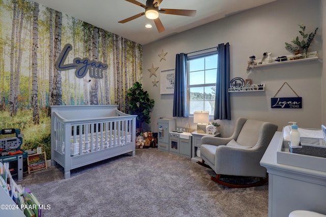 carpeted bedroom featuring ceiling fan and a nursery area