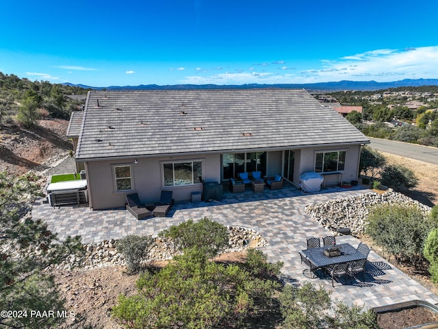 back of property with an outdoor living space, a patio area, and a mountain view