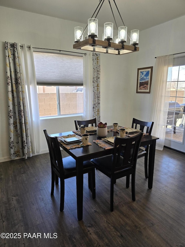 dining area with dark wood-style floors and an inviting chandelier