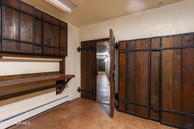 interior space featuring a baseboard radiator, a textured wall, and concrete flooring