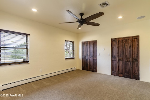 unfurnished bedroom featuring a baseboard heating unit, carpet, visible vents, recessed lighting, and two closets