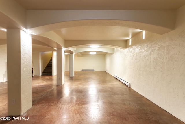 interior space featuring a baseboard heating unit, arched walkways, and a textured wall