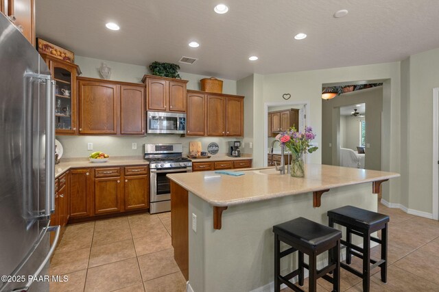 1109 N Half Hitch Rd, Prescott Valley, AZ 86314 - kitchen with stainless steel appliances, a sink, light countertops, a breakfast bar, and light tile patterned flooring