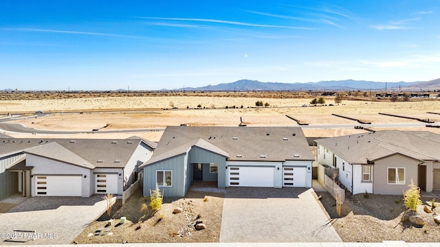 view of front of home featuring a desert view, a mountain view, decorative driveway, and a garage