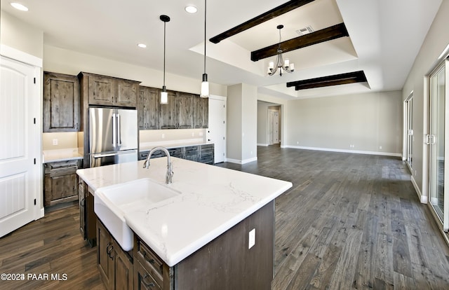 kitchen featuring dark hardwood / wood-style floors, stainless steel refrigerator, sink, hanging light fixtures, and a kitchen island with sink