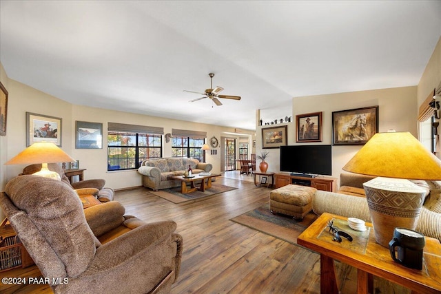 living room with hardwood / wood-style flooring, ceiling fan, and vaulted ceiling