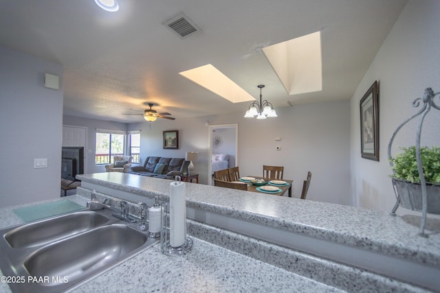 3070 Cascades Ct Unit 14C, Prescott, AZ 86301 - kitchen featuring a chandelier, a glass covered fireplace, a ceiling fan, pendant lighting, and a skylight