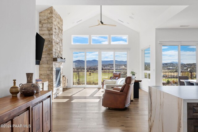 living room with a fireplace, plenty of natural light, high vaulted ceiling, and light hardwood / wood-style flooring