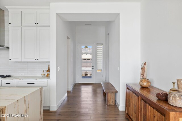 interior space featuring decorative backsplash, white cabinetry, dark wood-type flooring, and gas cooktop