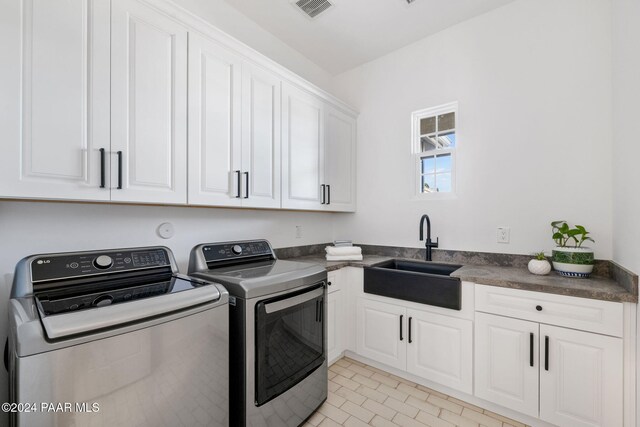 washroom featuring cabinets, sink, light tile patterned flooring, and washer and dryer