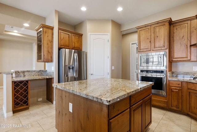 3280 Stone Cliff Ct, Prescott, AZ 86301 - kitchen with stainless steel appliances, light stone counters, a kitchen island, brown cabinets, and recessed lighting