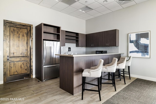 3280 Stone Cliff Ct, Prescott, AZ 86301 - kitchen featuring open shelves, freestanding refrigerator, light countertops, a breakfast bar area, and a peninsula