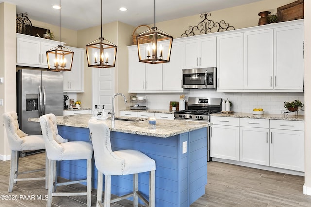 24757 N 175th Dr, Surprise, AZ 85387 - kitchen featuring a chandelier, stainless steel appliances, decorative backsplash, light wood-type flooring, and pendant lighting