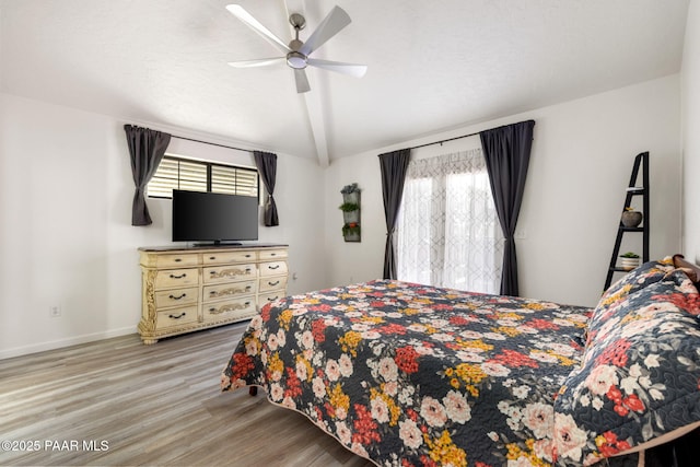 bedroom with baseboards, a ceiling fan, wood finished floors, and lofted ceiling