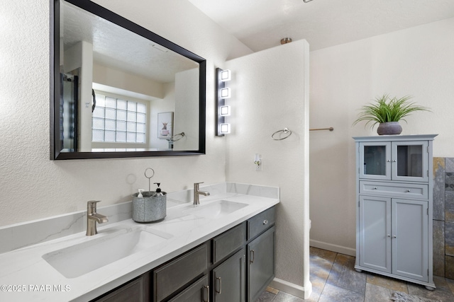 bathroom with double vanity, baseboards, and a sink