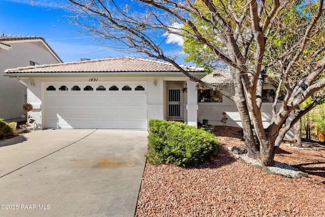 view of front of property featuring an attached garage, stucco siding, driveway, and a tiled roof