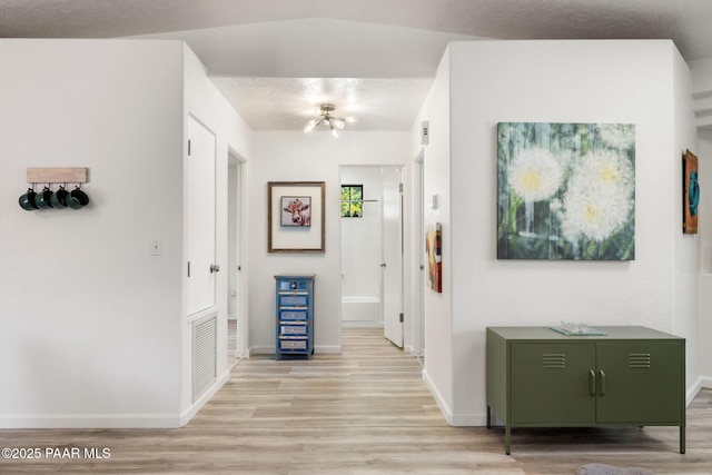 corridor with baseboards, light wood-style flooring, and visible vents