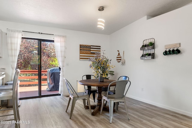 dining space featuring light wood-type flooring and baseboards