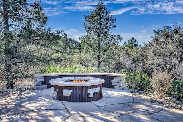 view of patio / terrace with an outdoor fire pit and a view of trees