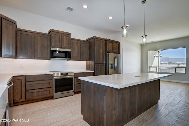 kitchen featuring tasteful backsplash, visible vents, stainless steel appliances, and wood tiled floor