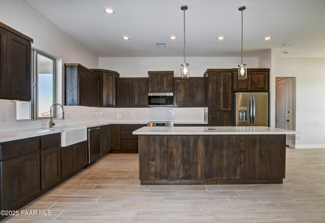 kitchen with a sink, a kitchen island, stainless steel appliances, dark brown cabinetry, and decorative backsplash