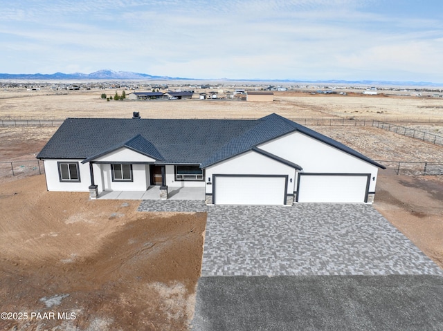 view of front facade with fence, driveway, roof with shingles, an attached garage, and a mountain view