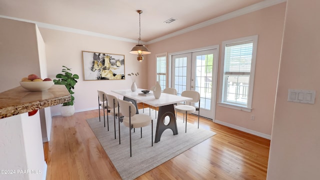 dining room featuring french doors, light wood-type flooring, and crown molding