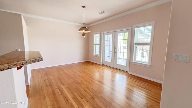 unfurnished dining area with light wood-type flooring, ornamental molding, and french doors