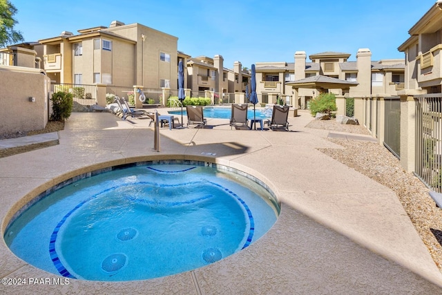 community pool featuring a hot tub, a residential view, fence, and a patio