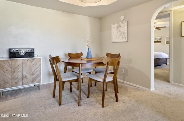 dining room with baseboards, arched walkways, and light colored carpet