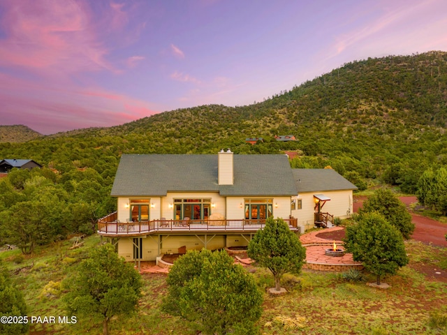2667 N Overlook Dr, Williams, AZ 86046 - rear view of property with an outdoor fire pit, a deck with mountain view, a chimney, a patio, and a view of trees