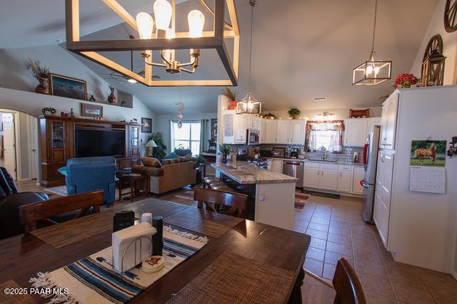 dining space featuring an inviting chandelier, tile patterned floors, and high vaulted ceiling