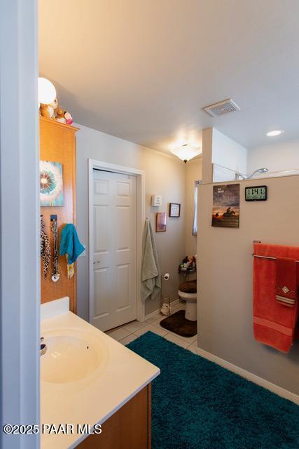 bathroom with vanity, baseboards, visible vents, tile patterned floors, and toilet