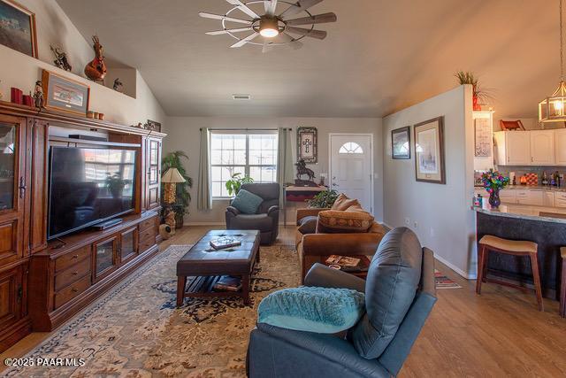 living room featuring wood finished floors, baseboards, and vaulted ceiling